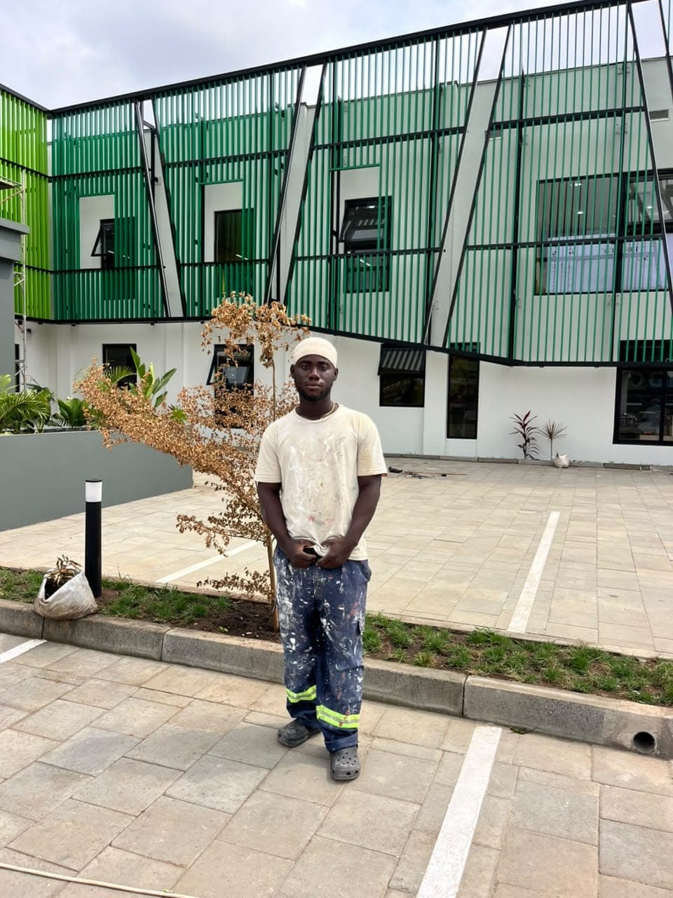Painter standing in front of a completed green and white commercial exterior
